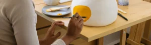 Person painting on pottery.