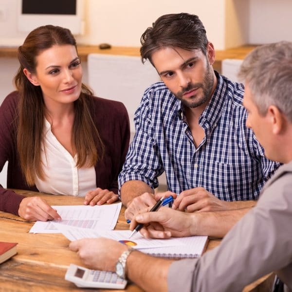 A couple sitting at a table receives advice from a lawyer.