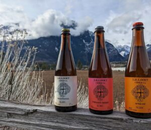 Three bottles of Lillooet Cider lined up on a fence.