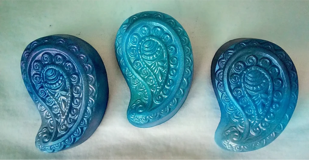 Three handmade soaps in blue paisley patterns.