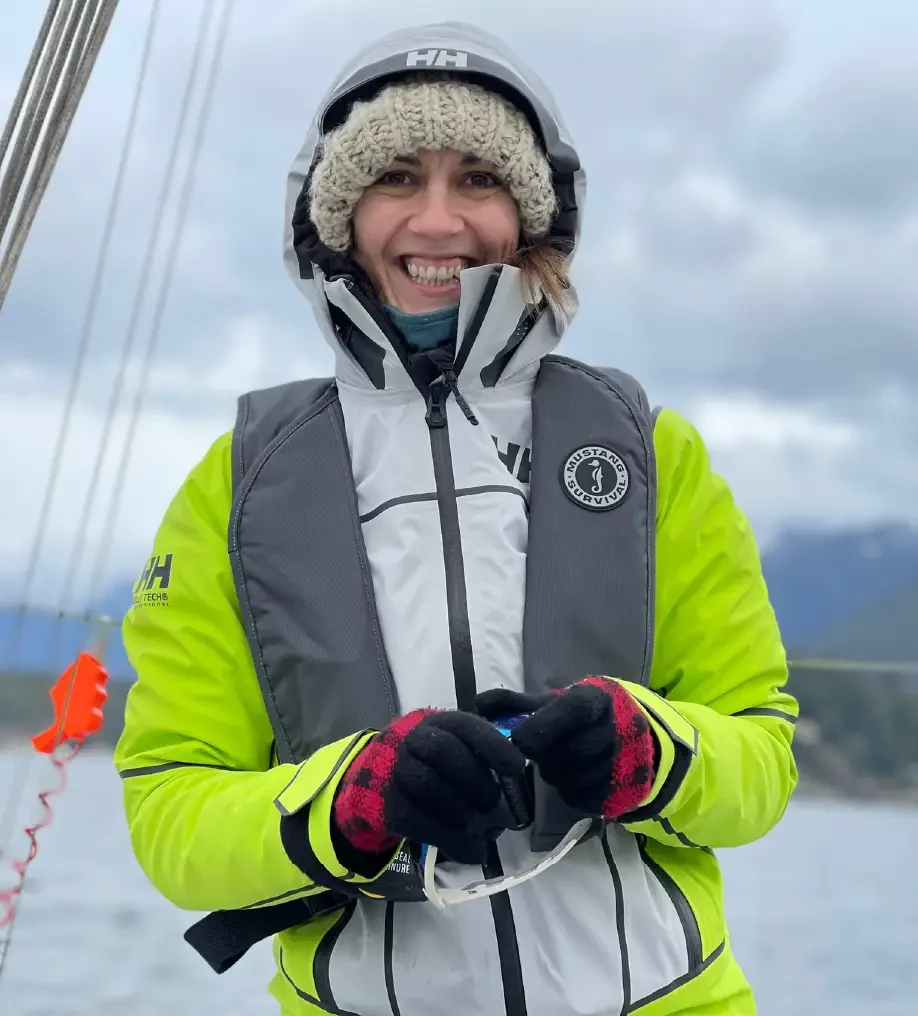 Sinead, fondatrice de She Sails Vancouver, sourit sur un voilier enveloppé dans des vêtements chauds.