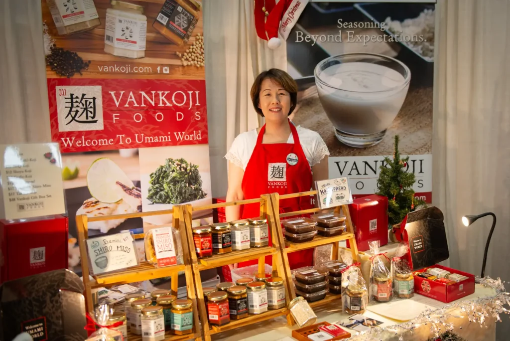 Vankoji Foods founder, Tonami, standing at her table at a craft fair.
