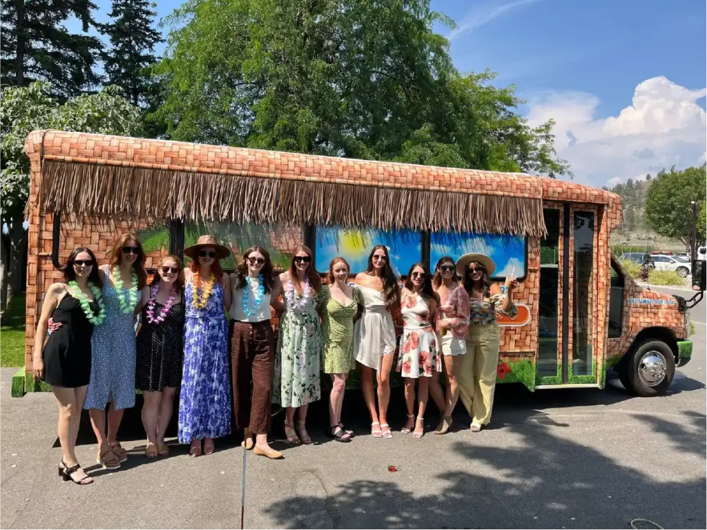 A group of tourists pose for a photo outside a tiki themed tour bus