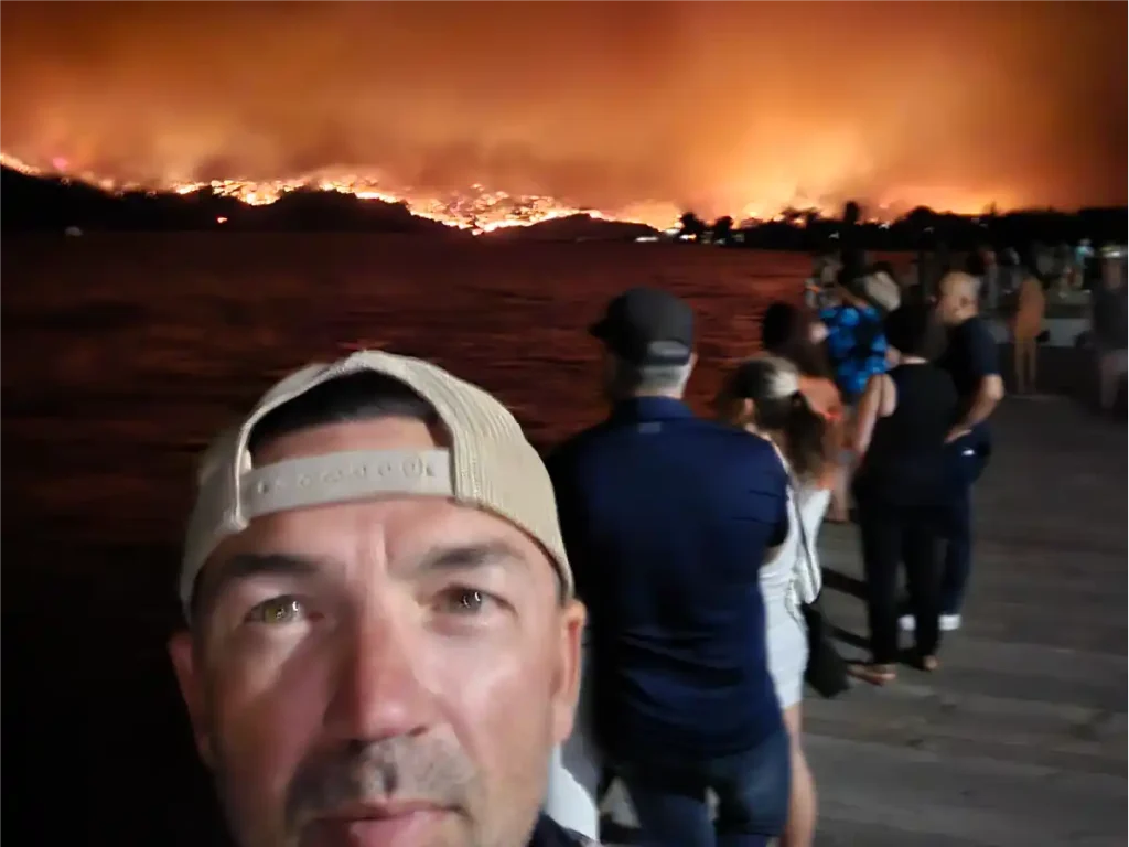 A selfie of business owner Jason with a wildfire in the background