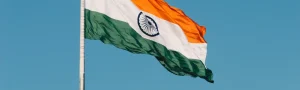 India's flag waving in the wind with a bright, blue sky behind it.