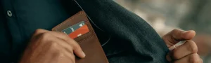 Person placing their wallet on an inside pocket of their jacket.
