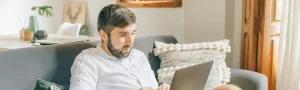 Person looking focused while working remotely on their laptop and sitting on a couch.