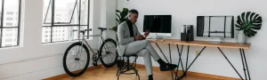 An entrepreneur sits at a desk and looks at a phone in a bright modern office.