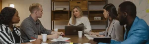 A non-profit board sitting and chatting around a table in an office.