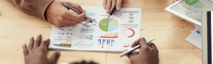 A chart on a table with many hands gathered around in discussion.