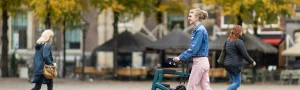 A person using a mobility device walks through an urban plaza.